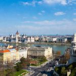 Panoráma Budapest belvárosára a Halászbástya mellől: jobbra a magyar Parlament gótikus épülete, középen a Duna és a Lánchíd, balra a pesti oldal házai kora tavaszi napsütésben.